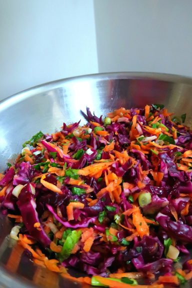 A vibrant salad featuring shredded purple cabbage, carrots, and herbs.