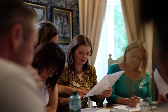 Group of people engaged in discussion, reviewing documents in a well-lit room.