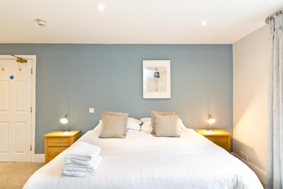 Modern bedroom with a large bed, bedside tables, and framed artwork on the wall.