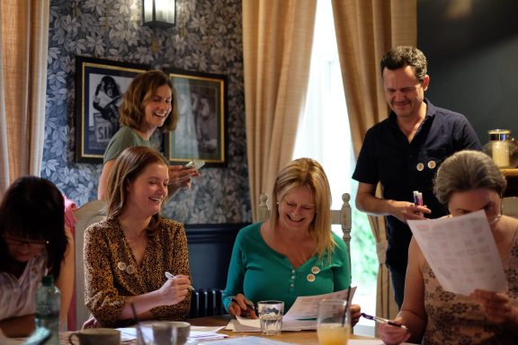 A group of women and a man engaged in a lively discussion around a table during an intensive Spanish Learning Weekend in Sheffield.